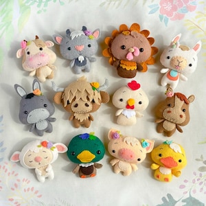Può includere: Una collezione di ornamenti fatti a mano in feltro a forma di animali della fattoria, tra cui una mucca, capra, tacchino, lama, asino, toro, pollo, cavallo, pecora, anatra, maiale e pulcino. Ogni ornamento è decorato con fiori e colori vari.