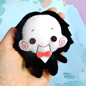 May include: A felt plush toy of a character with a black suit, white face, red bow tie, and a spiral pattern on the cheek. The character is holding a knife in its right hand. The text "PDF pattern by SokolFelt" is visible in the bottom right corner of the image.
