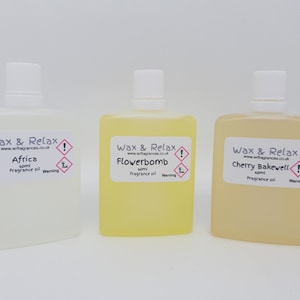 May include: Three clear glass bottles with white labels. The labels have the text "Wax & Relax" and the website address "www.wrfragrances.co.uk". The bottles contain fragrance oil in the scents "Africa", "Flowerbomb", and "Cherry Bakewell". Each bottle has a warning label.