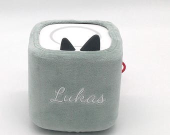 Könnte beinhalten: Ein weiches, hellgrünes, würfelförmiges Plüschtier mit dem Namen "Lukas" in Weiß gestickt. Die Oberseite hat eine weiße Oberfläche mit schwarzen Dreiecksformen und eine rote Schlaufe an der Seite. Das Spielzeug hat ein verspieltes, cartoonartiges Design.