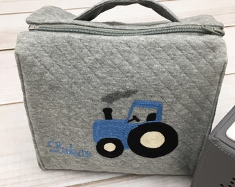 Könnte beinhalten: Graue gesteppte Tasche mit Reißverschluss, einem blauen Traktor und dem Namen "Lucas" auf der Vorderseite.