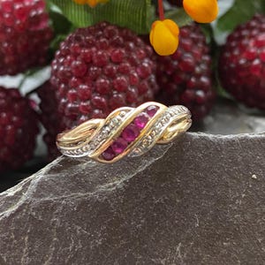 Op de afbeelding: Een gouden en zilveren ring met een rij robijnen die in een gedraaide band zijn gezet.