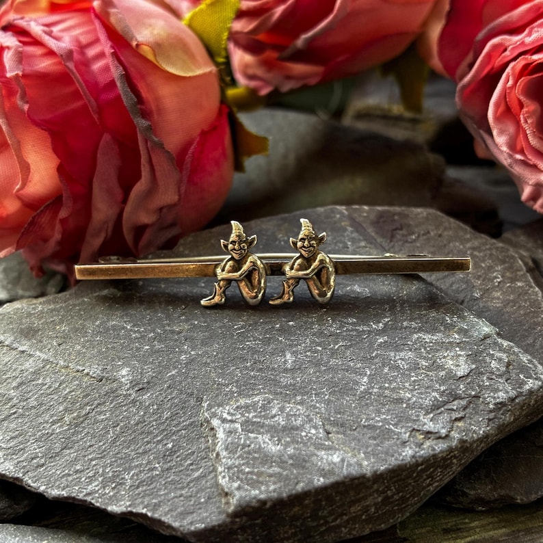 A cute sterling silver vintage brooch with two pixies or elf's sat on the bar with their knees up.
Measuring 45mm long
Stamped sterling silver- Circa 1940
In very good condition