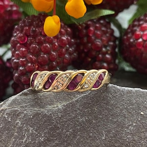 May include: A gold band ring with a twisted design featuring alternating red rubies and white diamonds.