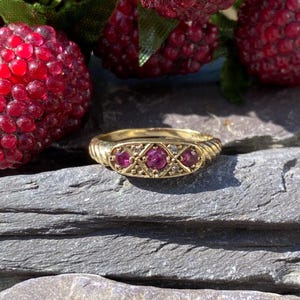 以下が含まれることがあります： 3つのルビーと小さなダイヤモンドが幾何学模様にセットされたゴールドリング