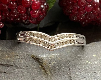 Pode incluir: Um anel de banda de prata com um design chevron cravejado com pequenos diamantes.