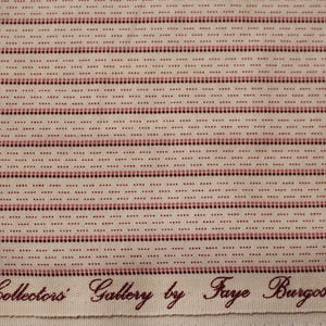 May include: A cream-colored fabric featuring horizontal rows of small, alternating dark red and light pink dots. The bottom edge displays the printed text: Collectors Gallery by Faye Burgos MARC.