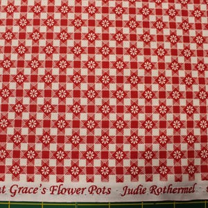 May include: Red and white checkered fabric with a floral pattern. The fabric has a gingham design with small white flowers at the intersections of the checks. The text "Aunt Grace's Flower Pots" is printed along the bottom edge.