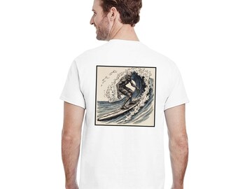May include: White t-shirt featuring a square graphic of a surfer riding a wave. The illustration is in shades of blue and gray, with the surfer in a wetsuit. The shirt is made of a soft, comfortable material.