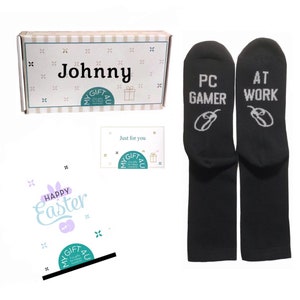 May include: A gift set featuring a box with the name "Johnny", a card that says "Just for you", and a pair of black socks. The socks have the words "PC GAMER" and "AT WORK" printed on them.