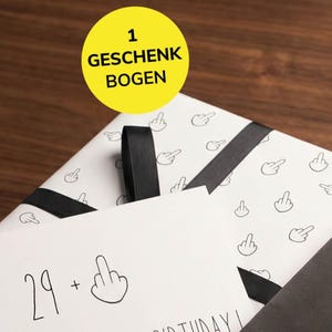 Könnte beinhalten: Ein weißes Geschenkpapier mit einem wiederkehrenden schwarzen Strichzeichnungsmuster von Mittelfingern, gebunden mit einem schwarzen Band. Vorne liegt eine weiße Karte mit dem Text 29 + einem Mittelfinger-Symbol.