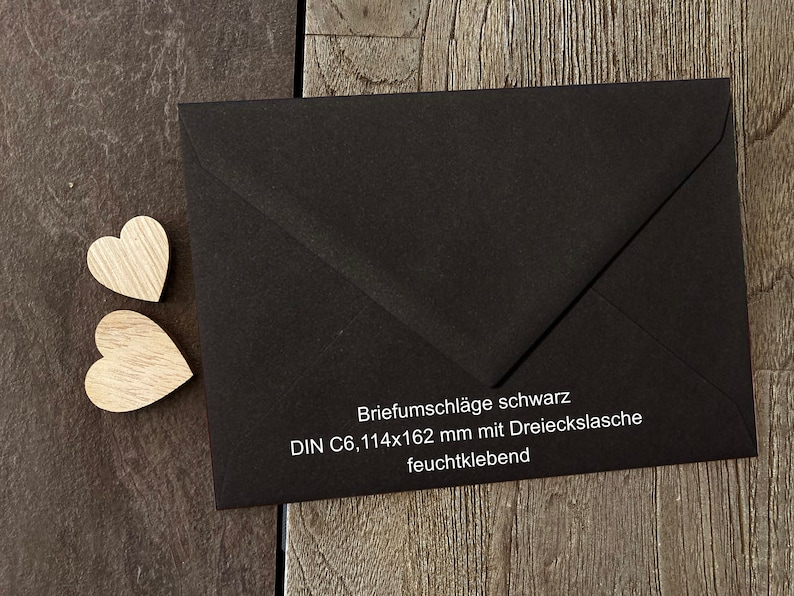 Op de afbeelding: Zwarte envelop met een witte flap en een wit label met de tekst "Briefumschl&auml;ge schwarz DIN C6, 114x162 mm mit Dreieckslasche feuchtklebend".