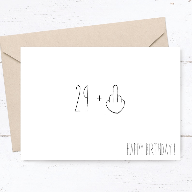 Op de afbeelding: Een witte kaart met zwarte tekst die "29 +" zegt en een eenvoudige tekening van een middelvinger. De kaart zegt ook "Happy Birthday!"