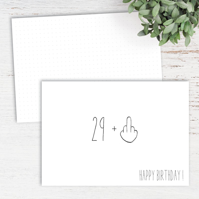 Op de afbeelding: Een witte kaart met zwarte tekst die "29 +" zegt, gevolgd door een hand die de middelvinger opsteekt. De kaart zegt ook "Happy Birthday!"