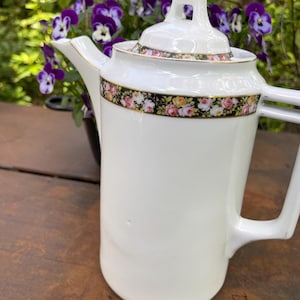 Caffettiera antica in stile Art Déco Bauhaus con bordo floreale, in porcellana bianca.