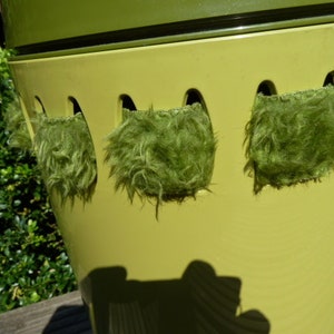 Peut inclure: Un pot en céramique vert et jaune avec quatre inserts en tissu vert duveteux. Le pot a un design unique avec des découpes pour les inserts.