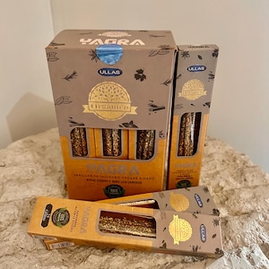 May include: Several boxes of Yagra brand incense sticks. The boxes are brown and gold, with the brand name and "Orgánico" printed on them. The boxes contain bundles of incense sticks.