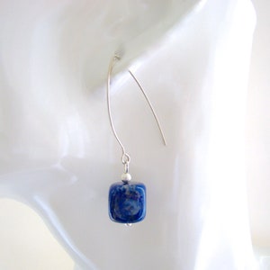 Könnte beinhalten: Ein Paar silberne Ohrringe mit einem quadratischen blauen Lapislazuli-Stein.