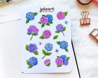 Peut inclure: Une feuille d'autocollants de fleurs d'hortensias avec des fleurs bleues et roses. La feuille d'autocollants est blanche avec le texte "ydxart Sticker Sheets" imprimé en marron.