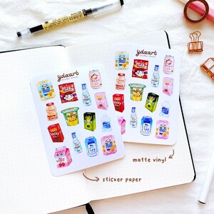 May include: Two sheets of stickers featuring illustrations of various Japanese snacks and drinks. The stickers are on a white background with the text "ydxart sticker sheets" printed on each sheet. The text "matte vinyl" is written on the right sheet and "sticker paper" is written on the left sheet.