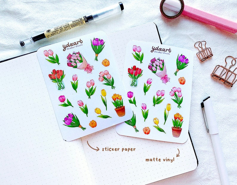 Op de afbeelding: Twee sticker vellen met illustraties van kleurrijke tulpen. De stickers bevatten boeketten, pot tulpen en individuele bloemen in roze, paars, rood en geel. De tekst "ydxart Sticker Sheets" is zichtbaar.