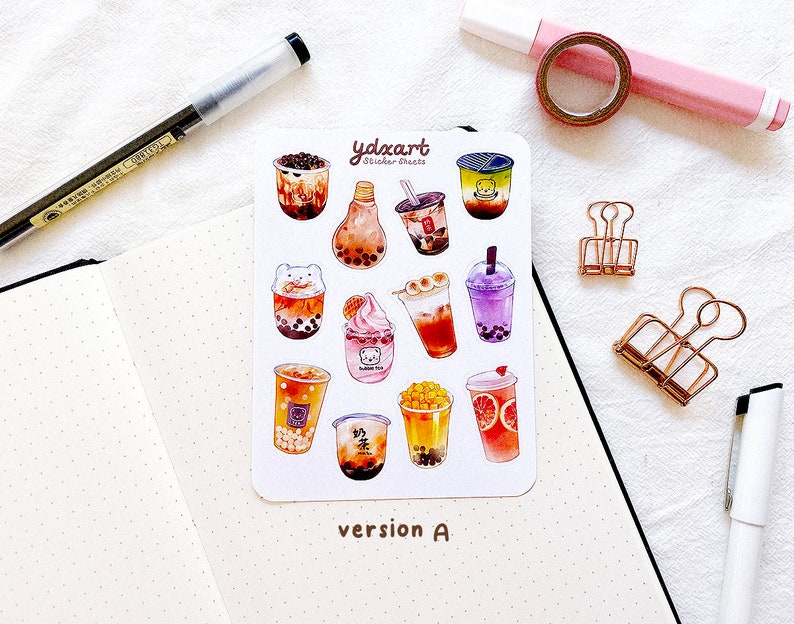 May include: A sheet of stickers featuring various bubble tea designs. The stickers are illustrated in a cartoon style with bright colors and feature different toppings and flavors. The sheet is labeled "ydxart Sticker Sheets" and "version A".