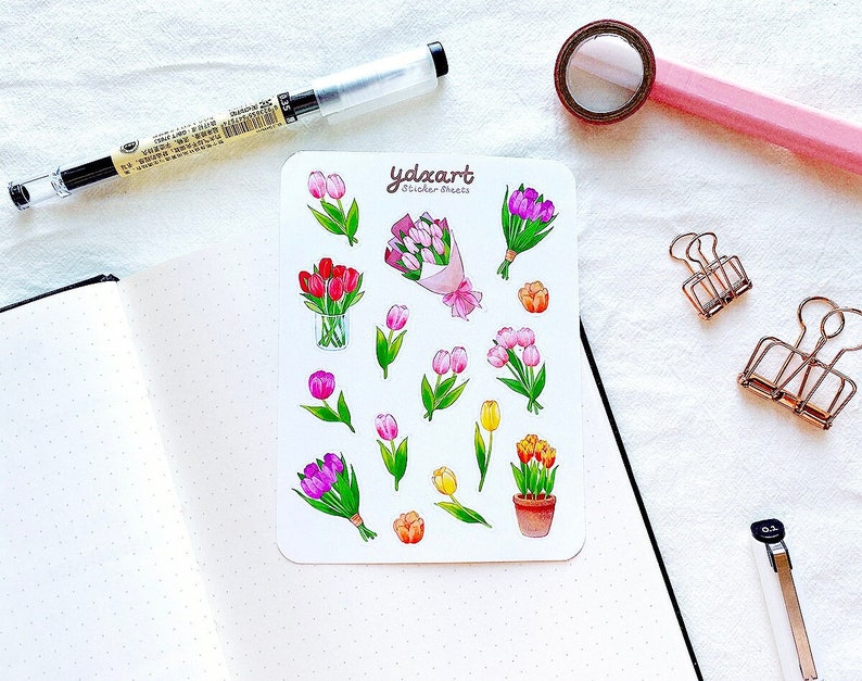 Op de afbeelding: Een stickervel met illustraties van tulpen in roze, rood, geel en paars. Sommige zijn in boeketten, andere in potten en sommige zijn losse bloemen. Het vel is gelabeld met "ydxart sticker sheets".