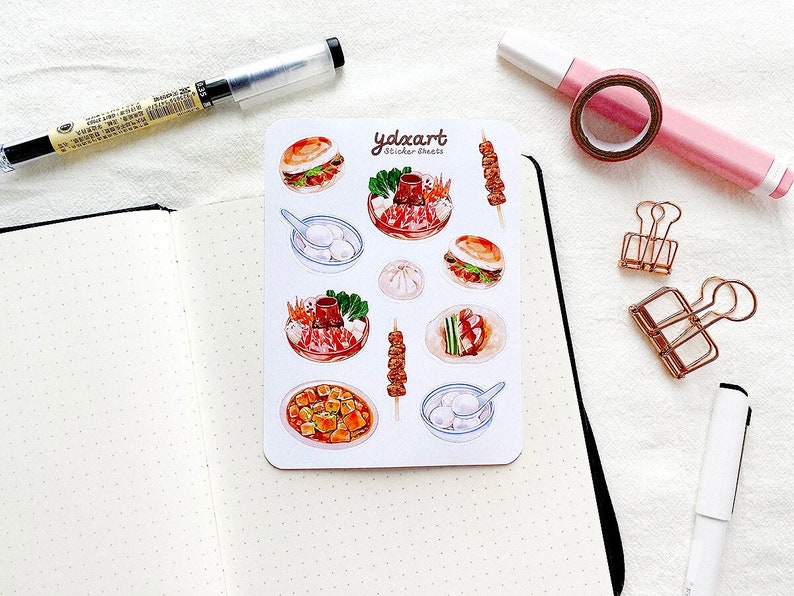 May include: A sheet of stickers featuring various Asian food illustrations, including dumplings, skewers, and a bowl of soup. The stickers are on a white background with the text "ydexart sticker-sheets" in black.