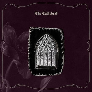 May include: A black and white pin featuring a cathedral window design, set against a black background with white stitching. The pin is displayed on a dark purple background with the text "The Cathedral".