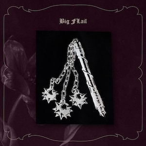 Può includere: Toppa quadrata nera con un'illustrazione bianca di un'arma a mazzafrusto. Il mazzafrusto ha tre sfere a punte collegate da catene a un'impugnatura. Il testo "Big Flail" è in alto.