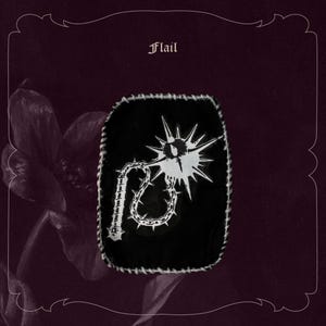 May include: Black patch with a white flail design, featuring a spiked ball and chain. The patch has a white stitched border and the word "Flail" at the top. Set against a dark purple background with floral accents.