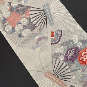 May include: A gray fabric with a repeating pattern of fans, flowers, and geometric shapes. The fabric has a subtle shimmer and a soft texture.