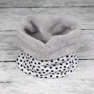 Könnte beinhalten: Ein weißer und schwarzer Tupfen-Halswärmer mit grauem Fleece-Futter.