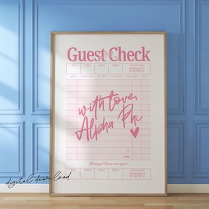 Puede incluir: Impresión enmarcada con un diseño rosa de "Guest Check", con el texto "with love, Alpha Phi" y un corazón. La impresión se muestra sobre una pared azul y un suelo de madera.