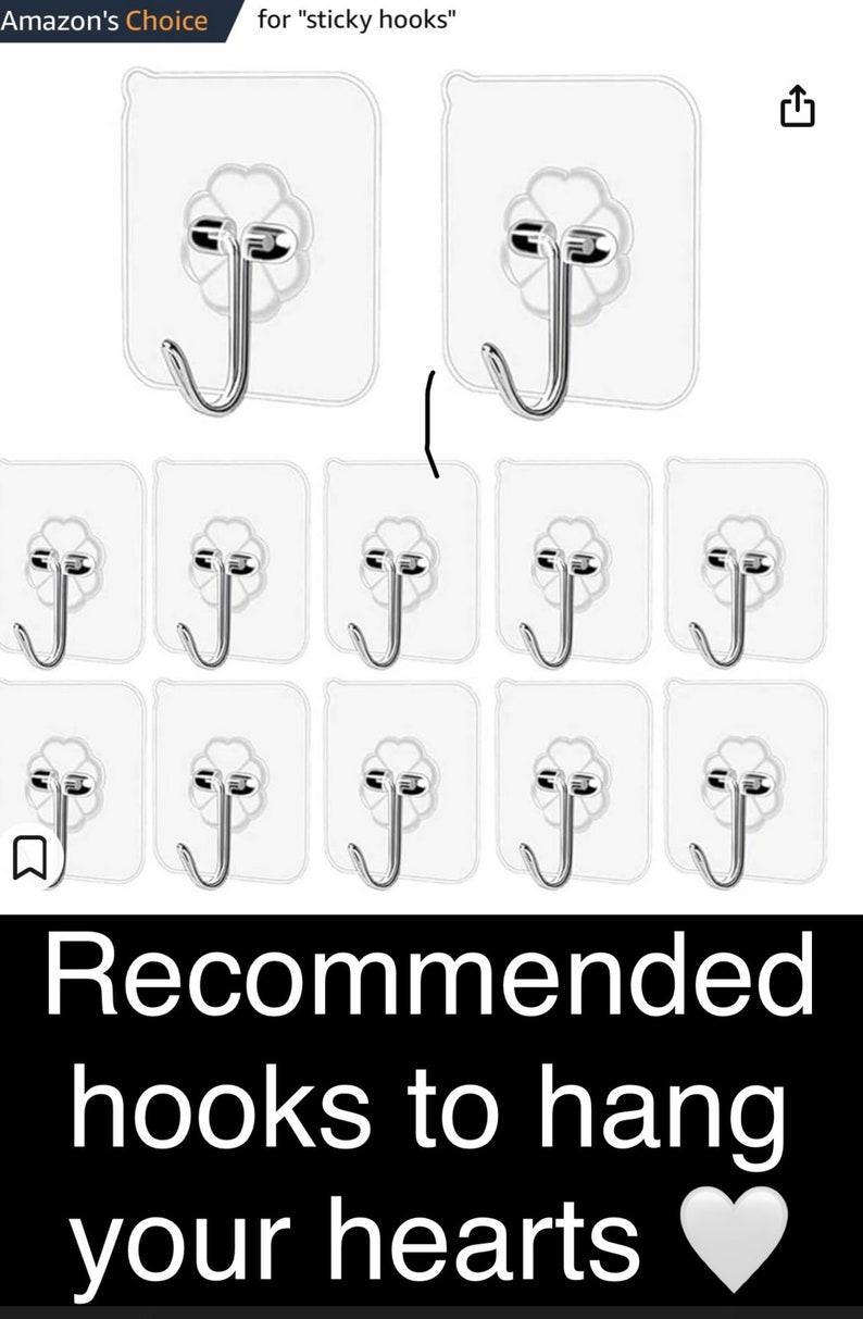May include: Ten clear, adhesive hooks with a silver metal hook. The hooks are designed to be stuck to a wall or other surface. The hooks are arranged in three rows of three hooks each. The text "Recommended hooks to hang your hearts" is displayed below the hooks.
