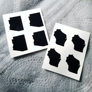 May include: Two sheets of white paper with black silhouette outlines of the state of Wisconsin. Each sheet has four outlines.