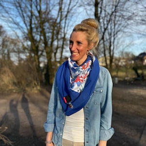 Könnte beinhalten: Eine Frau trägt ein blaues Jeanshemd mit einem blau-weiß gemusterten Schal. Der Schal hat rote und weiße Blumenmuster.