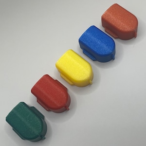 May include: Five small plastic caps in different colors: red, blue, yellow, red, and green. The caps are arranged in a row from left to right.