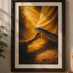 May include: A framed wall art print depicting a hand reaching towards the hem of a golden yellow fabric garment with a blue border and fringe. The scene is illuminated by warm, golden light rays against a textured, earthy ground surface.