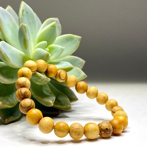 A wooden beaded bracelet with light brown beads. The bracelet is made of natural wood and has a simple design.