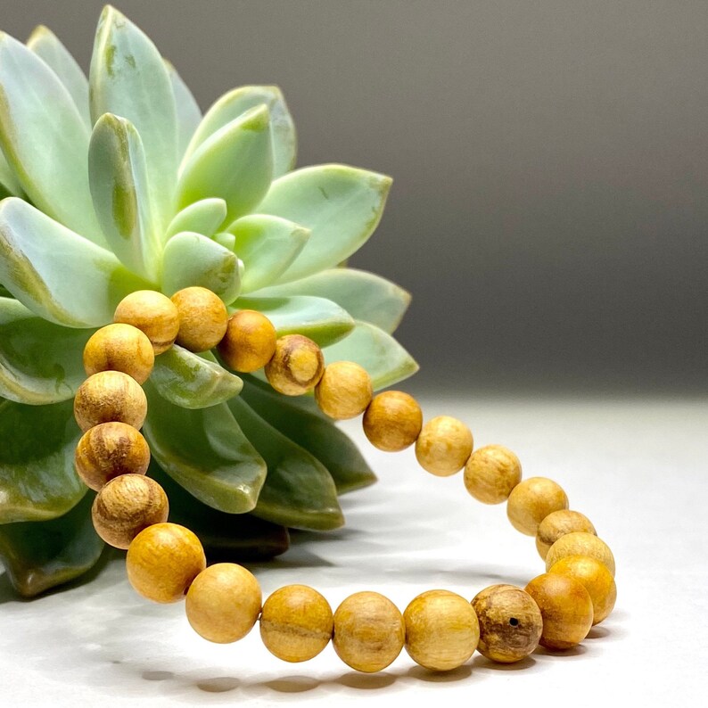 A wooden beaded bracelet with light brown beads. The bracelet is made of natural wood and has a simple design.