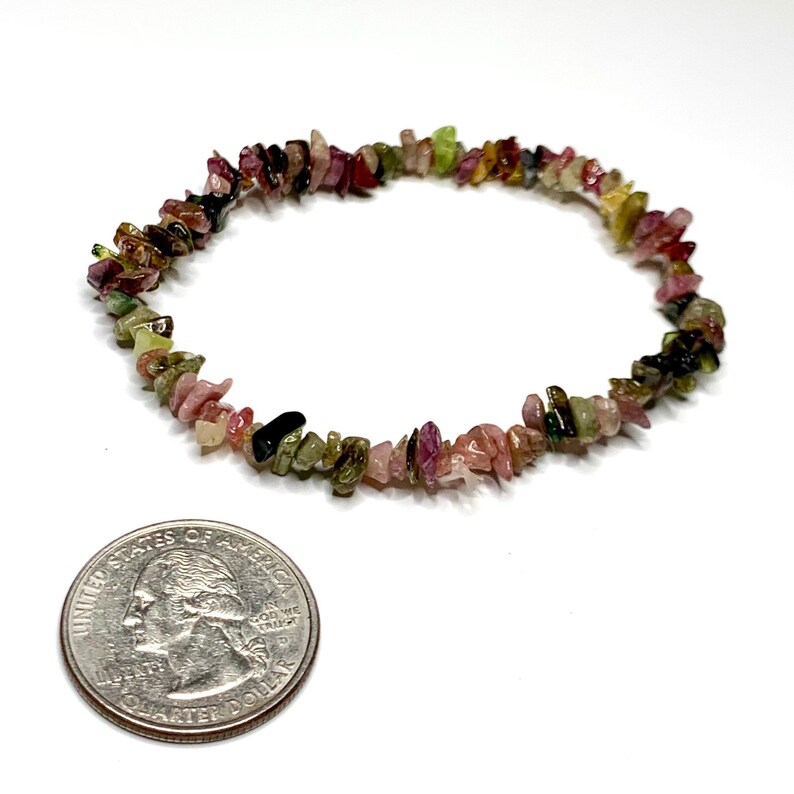 A bracelet made of small, chipped, multi-colored gemstones. The bracelet is about the size of a quarter. The gemstones are pink, green, black, and brown.