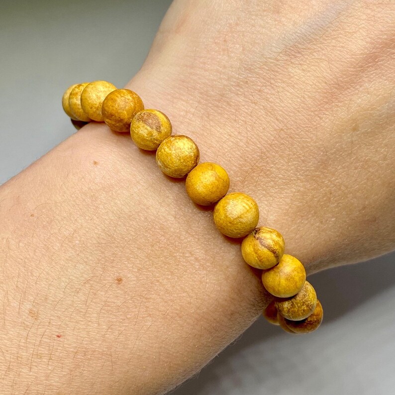A yellow beaded bracelet with brown streaks in the beads.