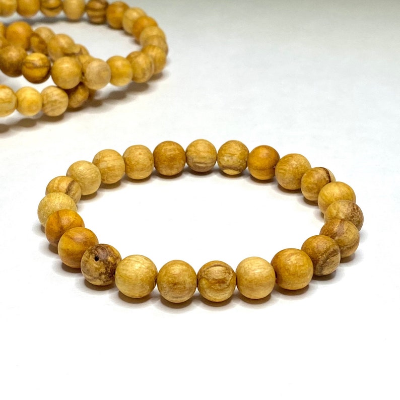 A wooden beaded bracelet with light brown beads. The bracelet is made of natural wood and has a simple design. A wooden beaded bracelet with light brown beads. The bracelet is made of natural wood and has a simple design.