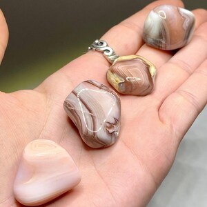 Four agate stones in various shades of pink and brown with white and brown banding.