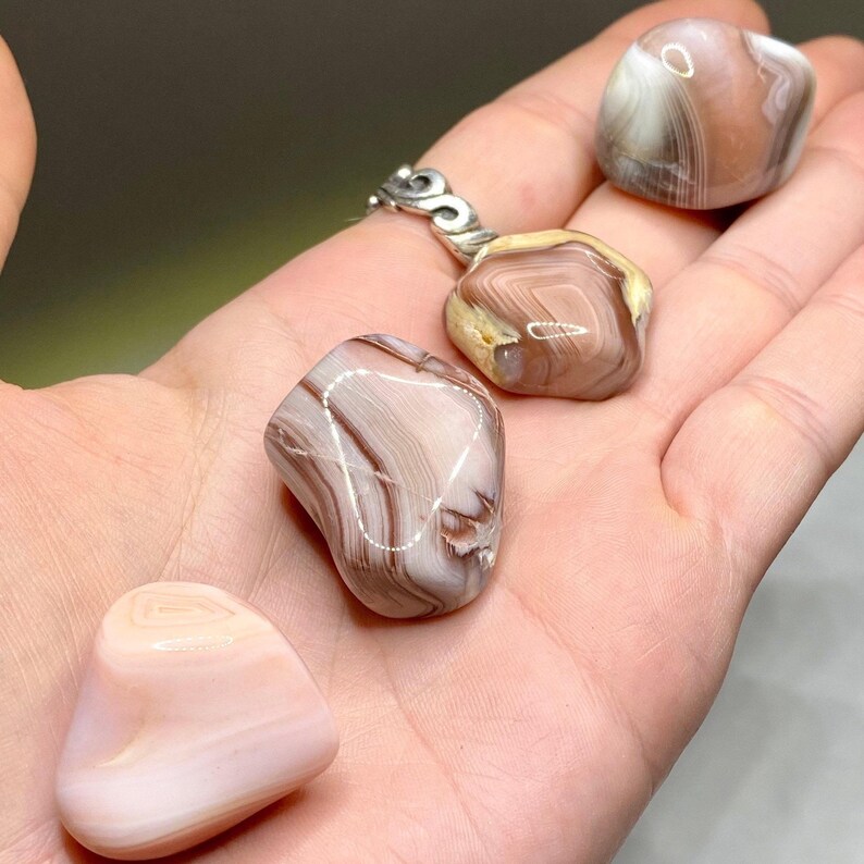 Four agate stones in various shades of pink and brown with white and brown banding.