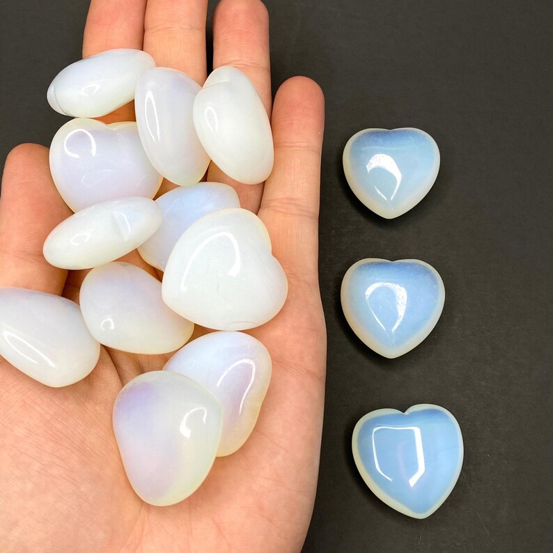A collection of heart shaped blue and white opalite stones on a black surface.