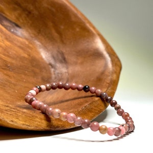 A pink and brown beaded bracelet on a wooden surface.