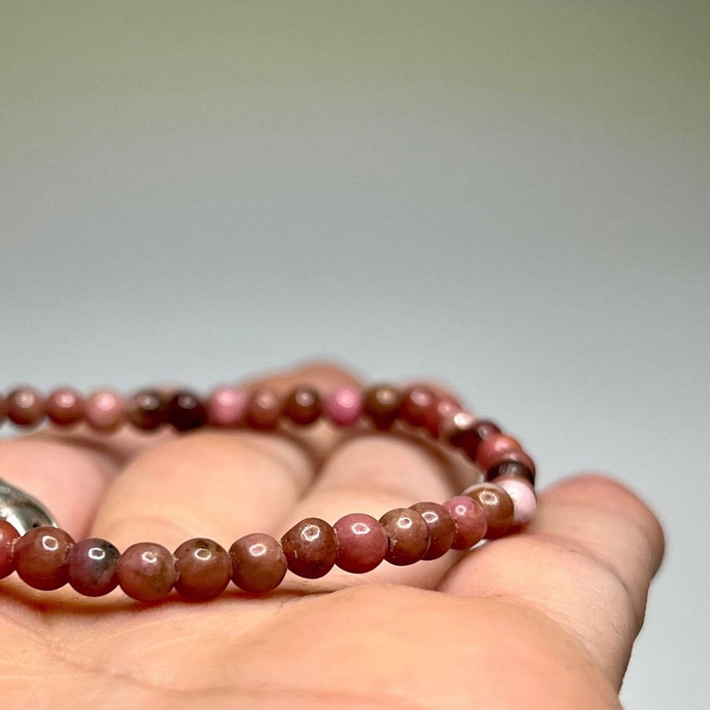 A pink and brown beaded bracelet with a silver clasp.
