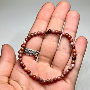 A pink and brown beaded bracelet made of small round stones.
